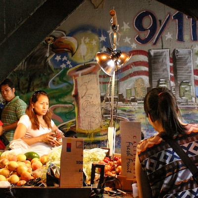 person buying fruit from a food cart in Queens